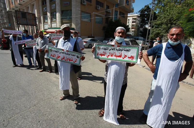 Families of Palestinian martyrs and wounded, take part in a protest against the Palestinian Authority's decision to cut their salaries for seven years, in front of the headquarters of Red cross in Gaza city, on June 21,...