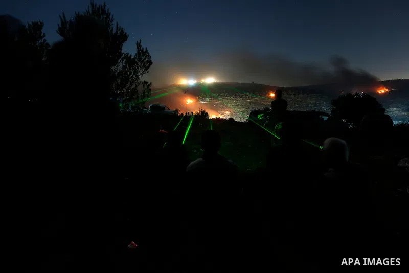 Palestinians shine laser torches during a night demonstration against the expansion of a Jewish settlement on the lands of Beita village, near the occupied West Bank city of Nablus, on June 21, 2021. Photo by Shadi Jarar...