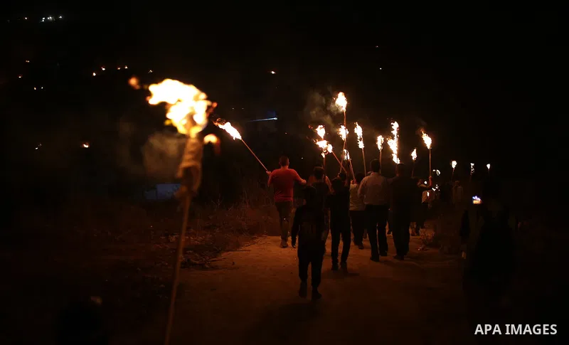 Palestinians carry torches during a night demonstration against the expansion of a Jewish settlement on the lands of Beita village, near the occupied West Bank city of Nablus, on June 23, 2021. Photo by Shadi Jarar'ah