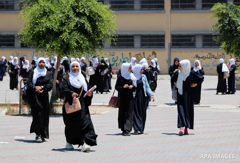 Palestinian female students stand outside their school after completing the final high school exam, in Rafah in the southern Gaza Strip on June 24, 2021, amid concerns about the spread of the novel coronavirus pandemic....