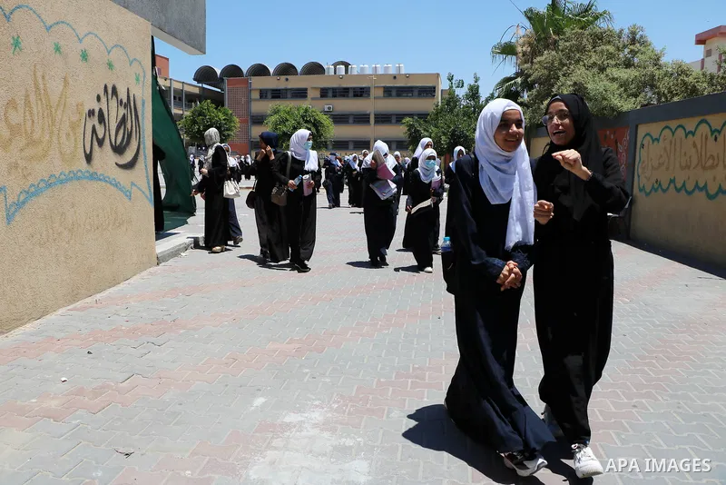 Palestinian female students stand outside their school after completing the final high school exam, in Rafah in the southern Gaza Strip on June 24, 2021, amid concerns about the spread of the novel coronavirus pandemic....