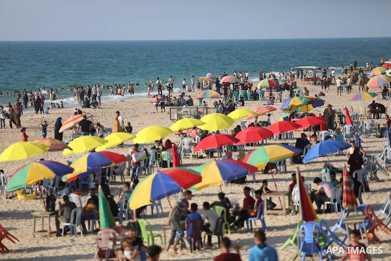 Palestinians enjoy the beach of the Mediterranean sea in Deir al-Balah in the center of Gaza Strip, on June 25, 2021. The beach is one of the few open public spaces in this densely populated city. Photo by Ashraf Amra