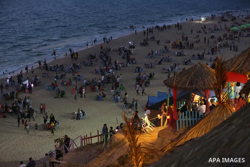 Palestinians enjoy the beach of the Mediterranean sea in Deir al-Balah in the center of Gaza Strip, on June 25, 2021. The beach is one of the few open public spaces in this densely populated city. Photo by Ashraf Amra