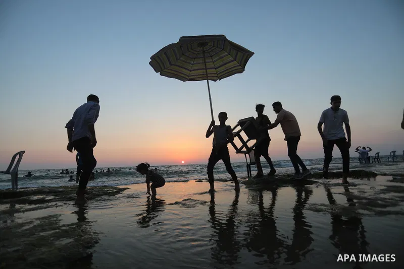 Palestinians enjoy the beach of the Mediterranean sea in Deir al-Balah in the center of Gaza Strip, on June 25, 2021. The beach is one of the few open public spaces in this densely populated city. Photo by Ashraf Amra