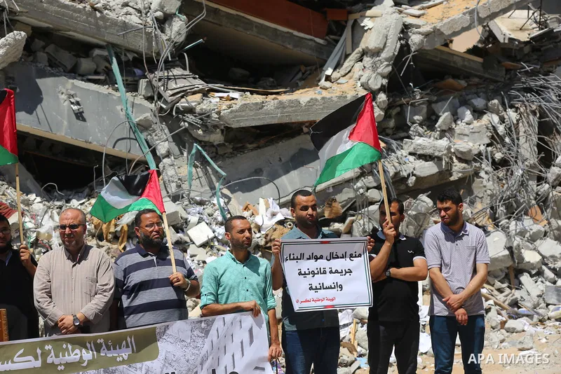 Palestinian members of the National and Islamic forces, take part in a protest to demand reconstruction and the entry of building materials, in front of Jala' Tower which destroyed which destroyed on May 15 during Israel...