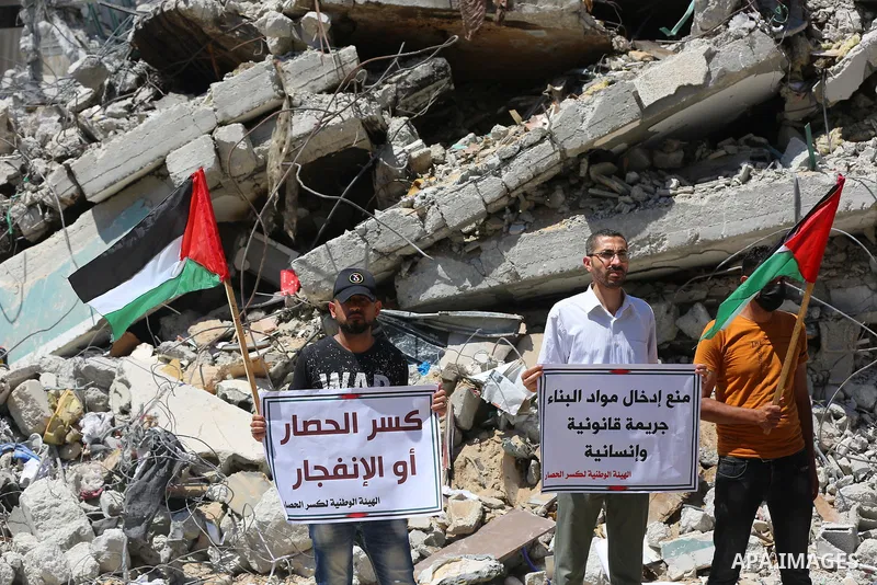 Palestinian members of the National and Islamic forces, take part in a protest to demand reconstruction and the entry of building materials, in front of Jala' Tower which destroyed which destroyed on May 15 during Israel...