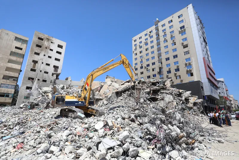 Palestinian members of the National and Islamic forces, take part in a protest to demand reconstruction and the entry of building materials, in front of Jala' Tower which destroyed which destroyed on May 15 during Israel...