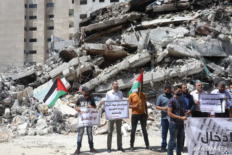 Palestinian members of the National and Islamic forces, take part in a protest to demand reconstruction and the entry of building materials, in front of Jala' Tower which destroyed which destroyed on May 15 during Israel...