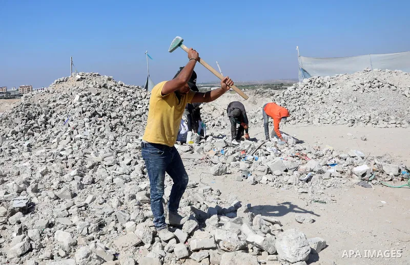 Palestinian workers crush stones and cement blocks from houses destroyed during the recent war on Gaza strip, in Gaza city on June 27, 2021. Owners of houses partially or totally destroyed during the recent war on Gaza a...