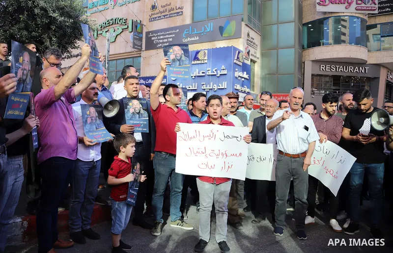 Demonstrators holding placards protest over the death of human rights activist Nizar Banat, in the West Bank city of Hebron on June 27, 2021. Photo by Ihab Alami