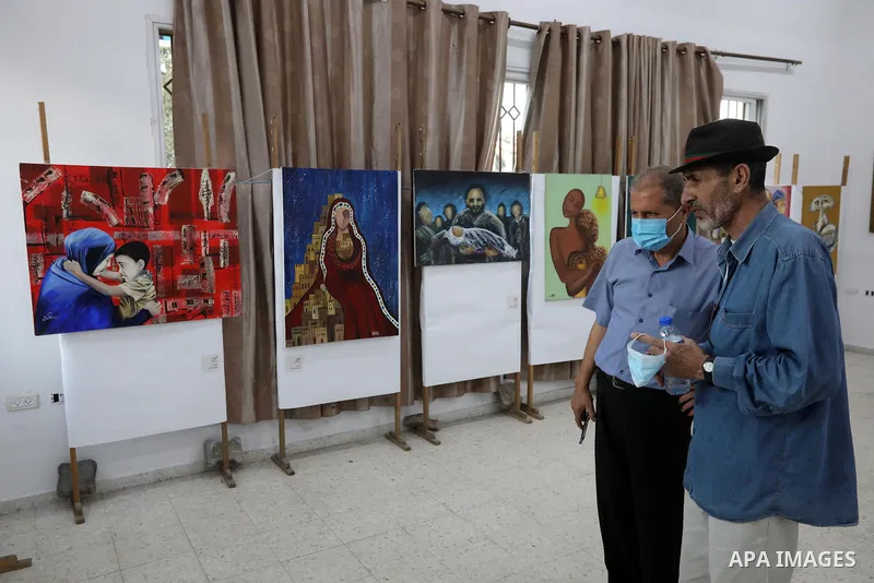 Palestinians attend an exhibition of paintings and sculptures, organized by the Gaza Center for Culture and Arts Association "The Third Gaza Contemporary Visual Arts Festival 2021" in Gaza City, on June 28, 2021. Photo b...