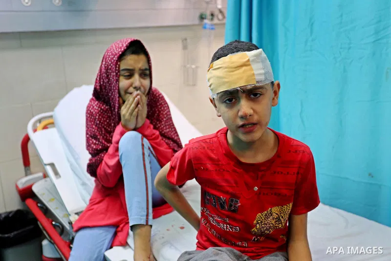 wounded Palestinians sit on a hospital bed at Al-Shifa Hospital, after an Israeli air strike struck their house located in al-Shati Refugee Camp without warning during the night, in Gaza City early on May 15, 2021. Israe...