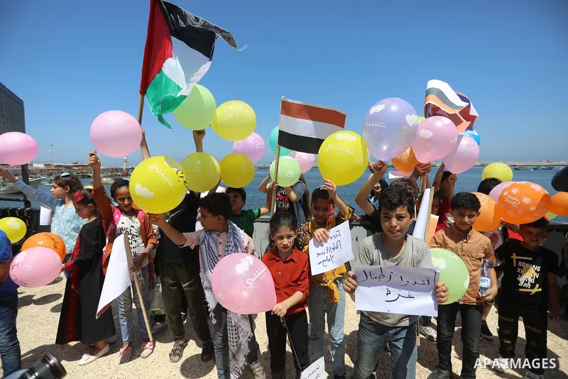 Palestinian children hold helium balloons as they take part in a rally, in the Gaza port, on June 30, 2021. Children from Gaza send messages to the countries of the world, expressing their wishes and aspirations to respe...