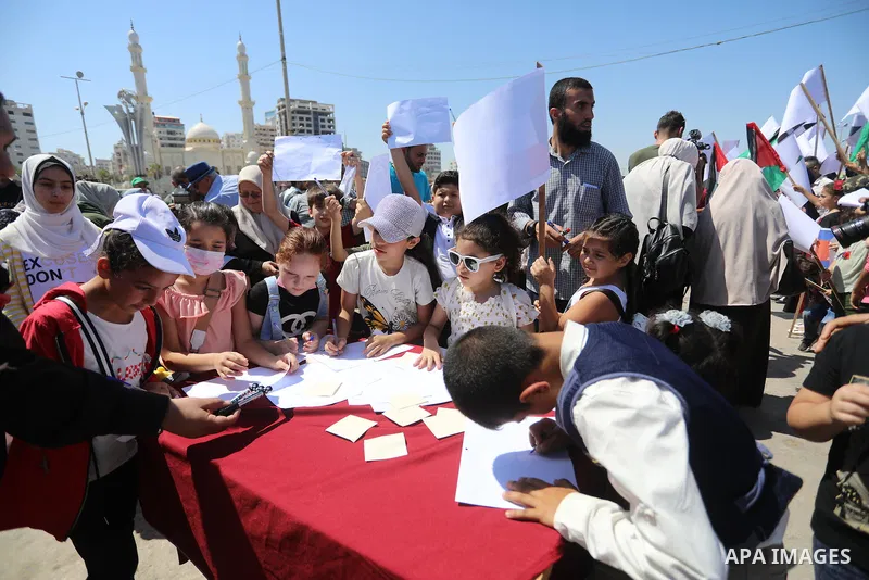 Palestinian children hold helium balloons as they take part in a rally, in the Gaza port, on June 30, 2021. Children from Gaza send messages to the countries of the world, expressing their wishes and aspirations to respe...