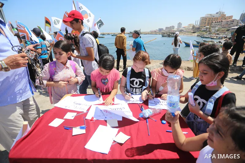 Palestinian children hold helium balloons as they take part in a rally, in the Gaza port, on June 30, 2021. Children from Gaza send messages to the countries of the world, expressing their wishes and aspirations to respe...