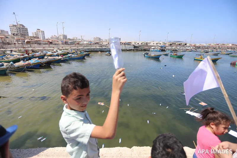 Palestinian children hold helium balloons as they take part in a rally, in the Gaza port, on June 30, 2021. Children from Gaza send messages to the countries of the world, expressing their wishes and aspirations to respe...