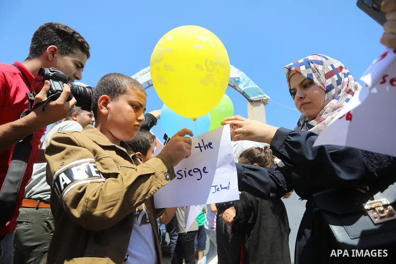 Palestinian children hold helium balloons as they take part in a rally, in the Gaza port, on June 30, 2021. Children from Gaza send messages to the countries of the world, expressing their wishes and aspirations to respe...