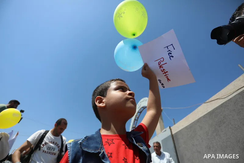 Palestinian children hold helium balloons as they take part in a rally, in the Gaza port, on June 30, 2021. Children from Gaza send messages to the countries of the world, expressing their wishes and aspirations to respe...