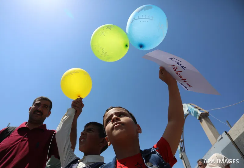 Palestinian children hold helium balloons as they take part in a rally, in the Gaza port, on June 30, 2021. Children from Gaza send messages to the countries of the world, expressing their wishes and aspirations to respe...