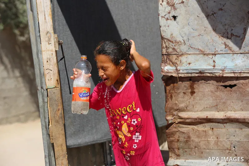 Palestinian children play with water during a hot weather wave, in a slum on the outskirts of the Gaza city on July 01, 2021. Photo by Ashraf Amra