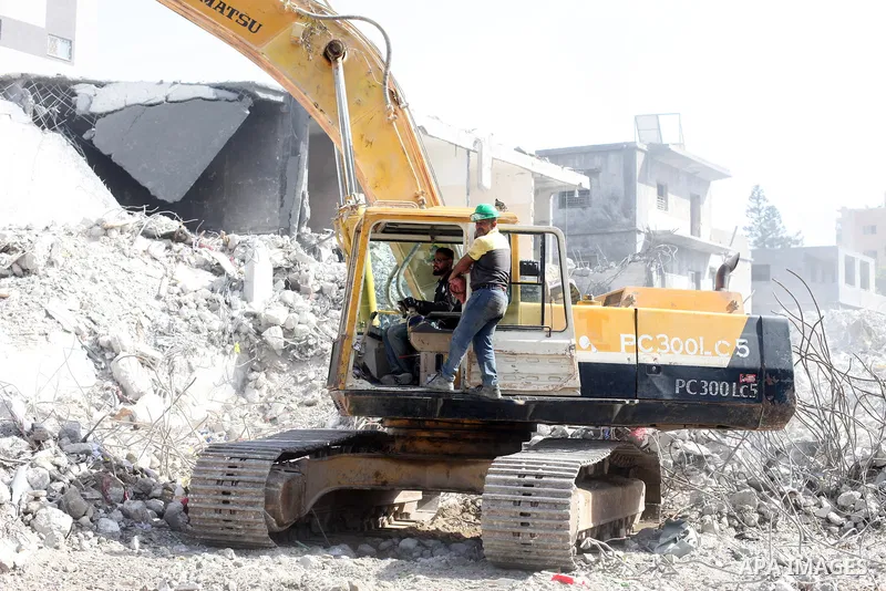 Egyptian workers and bulldozers sent from Egypt help to remove the rubble of Shorouq tower destroyed by Israeli air strikes on May, in Gaza City on July 03, 2021. Palestinian group Hamas said it will not accept any delay...