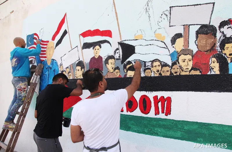 Palestinian artists paint a mural, in Gaza City on Junly 04, 2021. Gaza’s housing ministry said on Thursday that 16,800 housing units had been damaged. Of those, 1,800 had become unfit for living and 1,000 were destroyed...