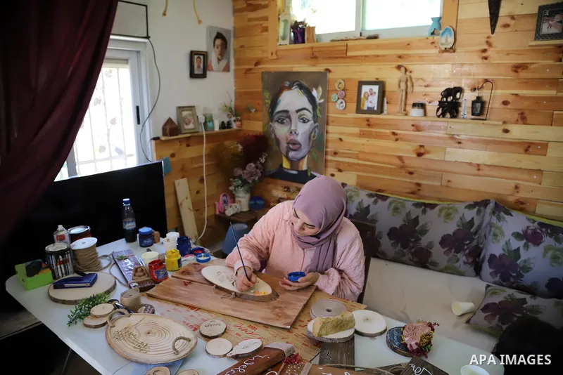 Palestinian artist Majd Abu Haikal, works on wood to makes gifts at her home in the West Bank city of Hebron on July 10, 2021. Abu Haikal works to recycle wood into gifts and paintings. Photo by Ihab Alami