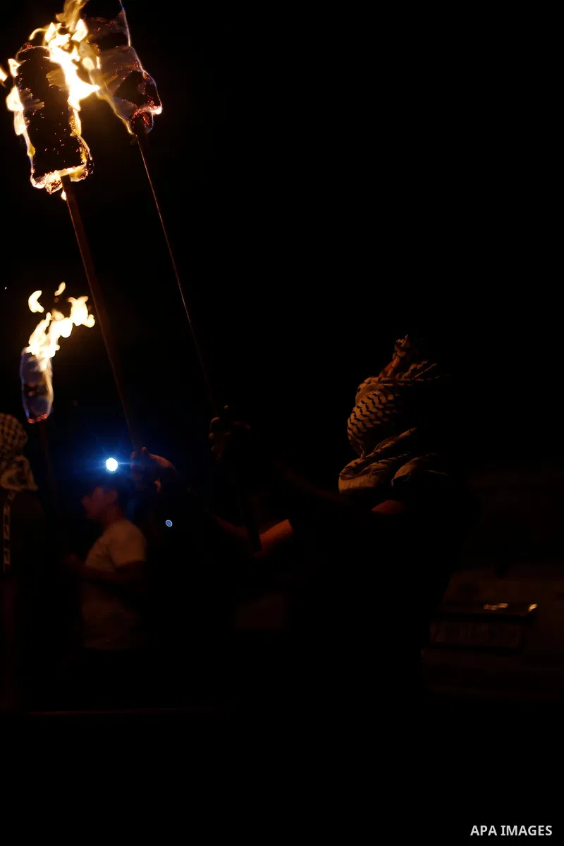Palestinian protesters gather with torches during a night demonstration in the town of Beita, near the West Bank city of Nablus, opposite the newly-established Israeli wildcat settler outpost of Eviatar, on July 11, 2021...