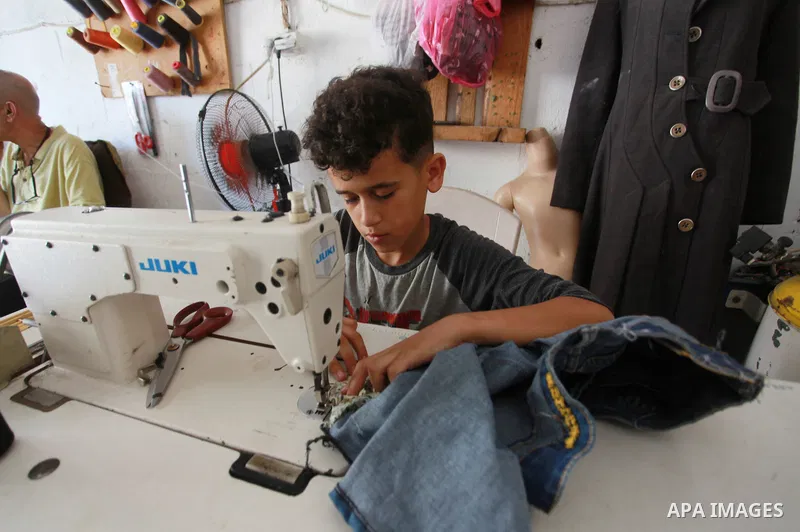 Palestinian boy Ahmed Abbas, 13, works at his father's sewing workshop at the Shati refugee camp in Gaza City, July 12, 2021. Ahmed has become the youngest tailor or fashion designer in the Gaza Strip. Abbas has mastered...