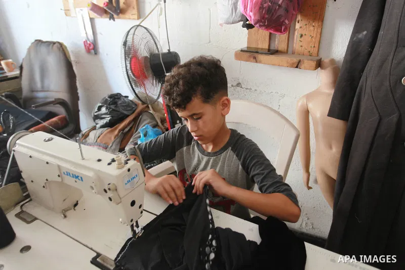 Palestinian boy Ahmed Abbas, 13, works at his father's sewing workshop at the Shati refugee camp in Gaza City, July 12, 2021. Ahmed has become the youngest tailor or fashion designer in the Gaza Strip. Abbas has mastered...