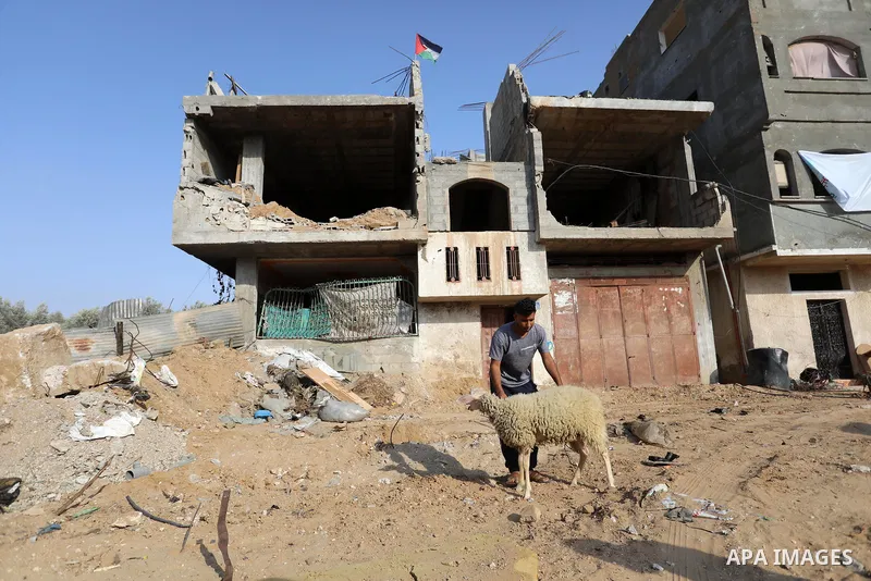 A Palestinian man holding a sheep ahead of Eid al-Adha festival, near rubbles of his house which was destroyed by airstrikes during an 11-day war between Hamas and Israel last May in Khan Yunis in the southern Gaza Strip...