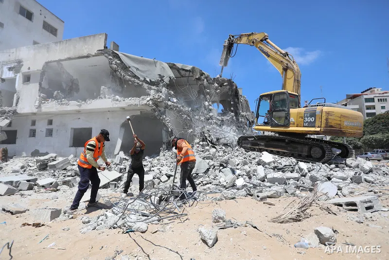 Palestinian workers remove the rubbles of buildings recently destroyed by Israeli strikes in Gaza City on July 27, 2021. Human Rights Watch investigated three Israeli strikes that killed 62 Palestinian civilians where th...