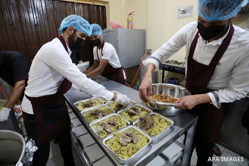 Palestinian volunteers prepare food to be distributed for free at Takiya, in Khan Younis in the southern Gaza Strip on July 29, 2021. The Takiya operates only three days a week, and serving meat, fish and chicken meals....