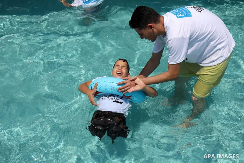 Palestinian amputee youths and children swim in a pool during a summer camp "Ability camp", in Gaza city on August 1, 2021. Photo by Ashraf Amra