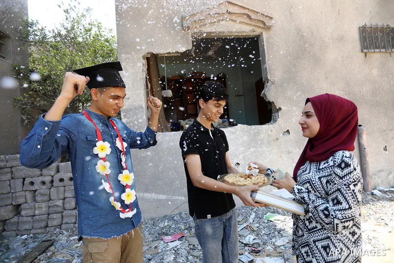 A Palestinian high school student, Yahya Al-Sakka, 94.9%, celebrates with his family after he success in final exams known as ''Tawjihi'' on the rubble of his room which was demaged by Israeli airstrikes during the recen...