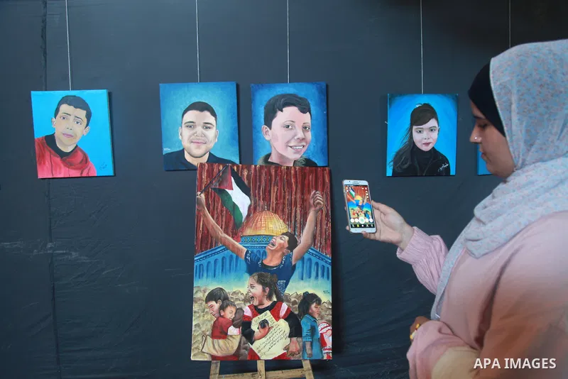Palestinians attend an art gallery contains 67 paintings depicting children who were killed during the recent 11-days conflict between Israel and Hamas, in Gaza city on August 10, 2021. Photo by Omar Ashtawy