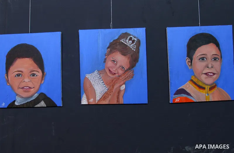 Palestinians attend an art gallery contains 67 paintings depicting children who were killed during the recent 11-days conflict between Israel and Hamas, in Gaza city on August 10, 2021. Photo by Omar Ashtawy