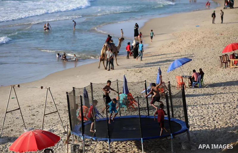 Palestinians enjoy their time at the beach of Deir al-Balah sea, in the center of Gaza Strip, during a hot day on August 11, 2021. The beach is one of the few open public spaces in this densely populated city. Photo by A...
