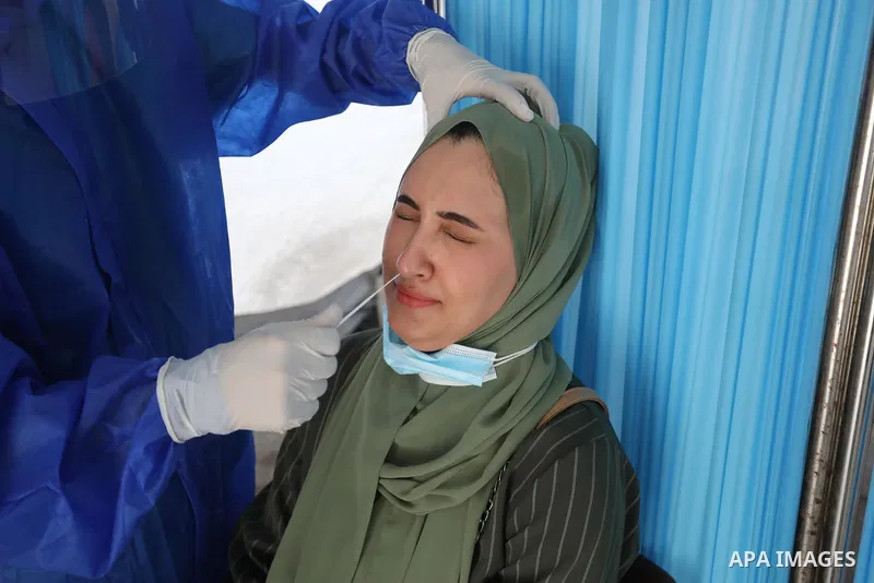 A Palestinian health worker collects a swab sample from a person for Covid-19 test, at a temporary vaccination centre set up, in Deir al-Balah in the center of Gaza strip on August 22, 2021. Photo by Ashraf Amra