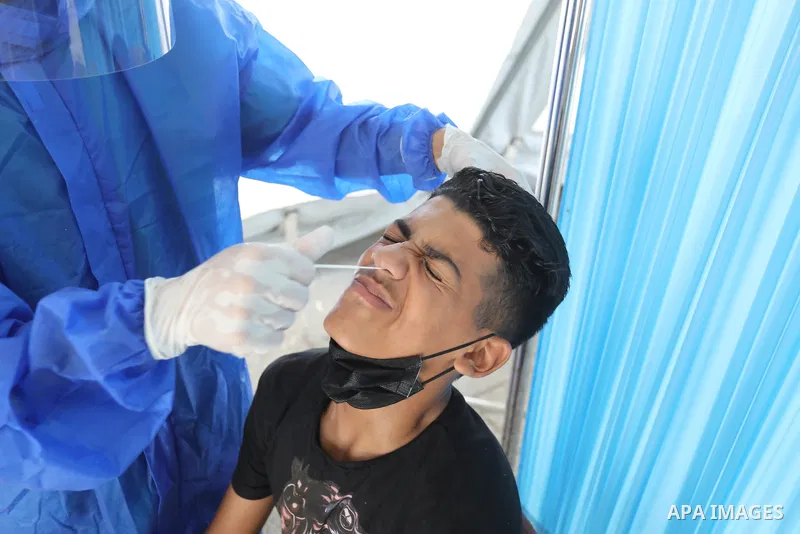 A Palestinian health worker collects a swab sample from a person for Covid-19 test, at a temporary vaccination centre set up, in Deir al-Balah in the center of Gaza strip on August 22, 2021. Photo by Ashraf Amra