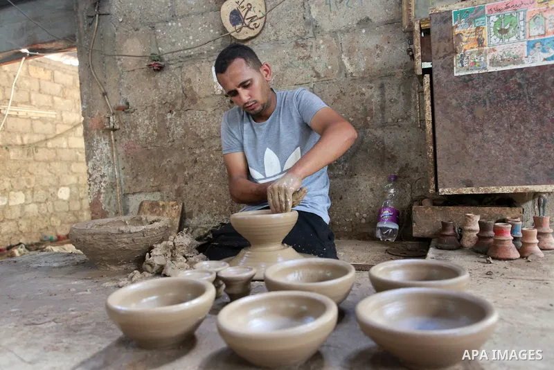A Palestinian pottery worker makes earthenware vases at a pottery workshop, in Gaza city on August 23, 2021. Pottery is an ancient and traditional craft in Gaza. Local workshops usually produce products such as bowls, pi...