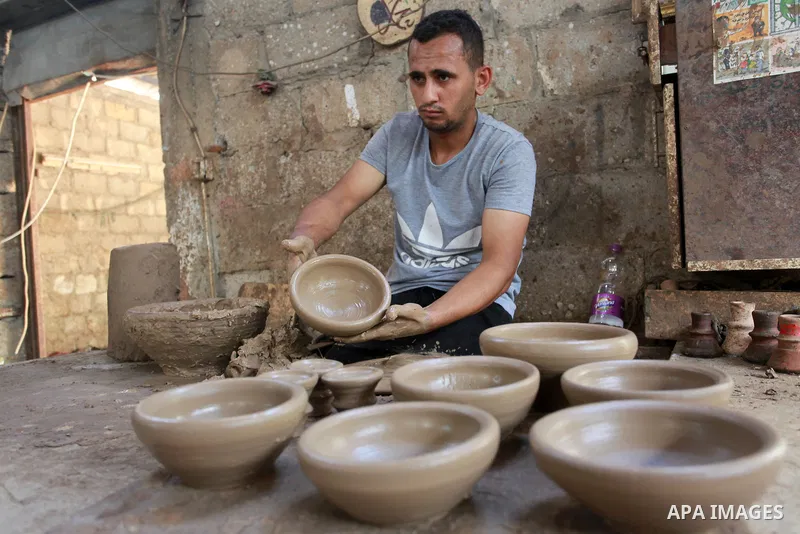 A Palestinian pottery worker makes earthenware vases at a pottery workshop, in Gaza city on August 23, 2021. Pottery is an ancient and traditional craft in Gaza. Local workshops usually produce products such as bowls, pi...