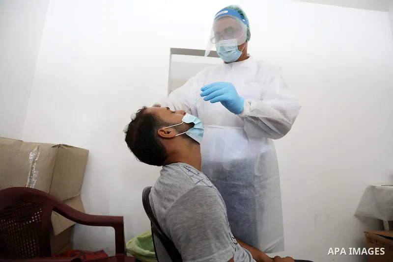 A Palestinian health worker collects a swab sample from a person for Covid-19 test, at a temporary vaccination centre set up in Khan Younis in the southern Gaza Strip on August 23, 2021. Palestinian health officials on M...