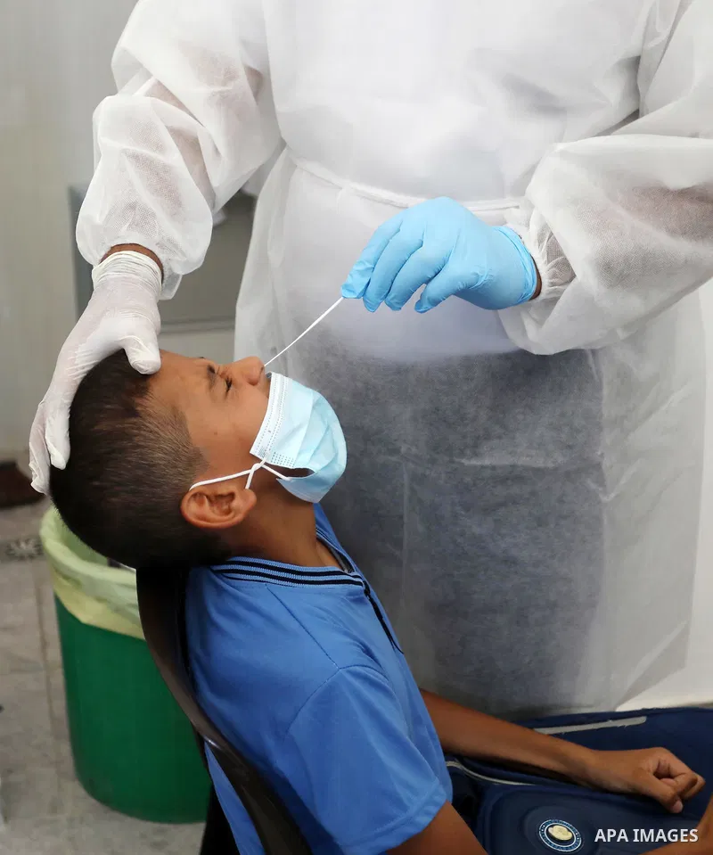 A Palestinian health worker collects a swab sample from a person for Covid-19 test, at a temporary vaccination centre set up in Khan Younis in the southern Gaza Strip on August 23, 2021. Palestinian health officials on M...