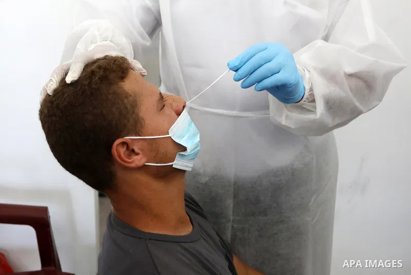 A Palestinian health worker collects a swab sample from a person for Covid-19 test, at a temporary vaccination centre set up in Khan Younis in the southern Gaza Strip on August 23, 2021. Palestinian health officials on M...