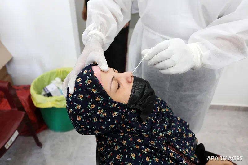 A Palestinian health worker collects a swab sample from a person for Covid-19 test, at a temporary vaccination centre set up in Khan Younis in the southern Gaza Strip on August 23, 2021. Palestinian health officials on M...