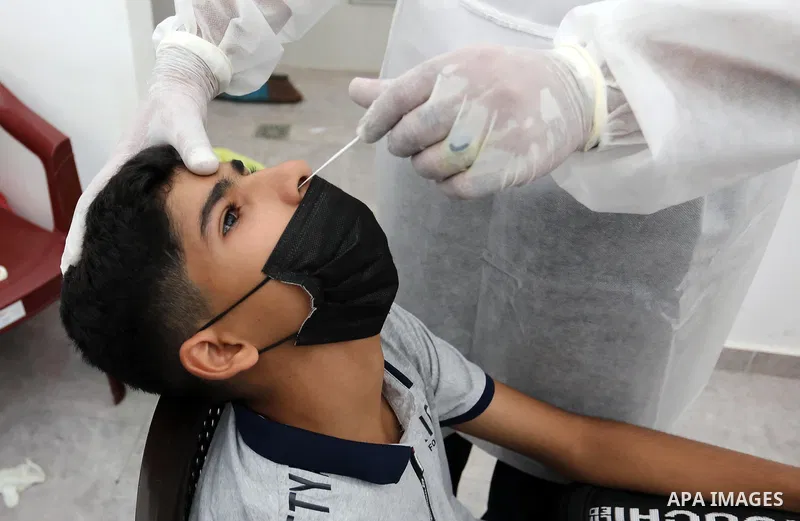 A Palestinian health worker collects a swab sample from a person for Covid-19 test, at a temporary vaccination centre set up in Khan Younis in the southern Gaza Strip on August 23, 2021. Palestinian health officials on M...