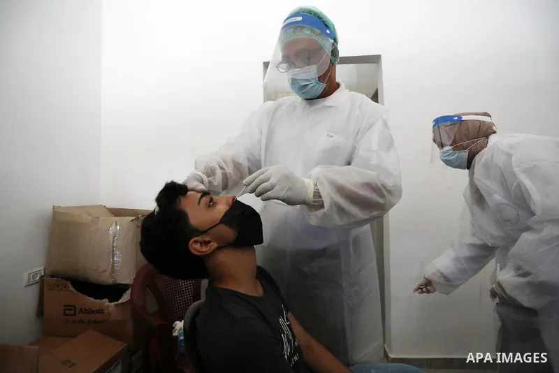 A Palestinian health worker collects a swab sample from a person for Covid-19 test, at a temporary vaccination centre set up in Khan Younis in the southern Gaza Strip on August 23, 2021. Palestinian health officials on M...