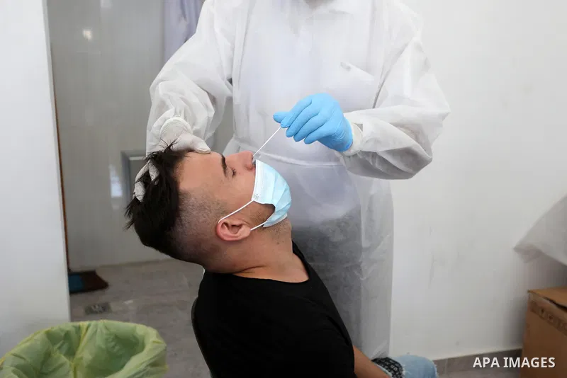 A Palestinian health worker collects a swab sample from a person for Covid-19 test, at a temporary vaccination centre set up in Khan Younis in the southern Gaza Strip on August 23, 2021. Palestinian health officials on M...