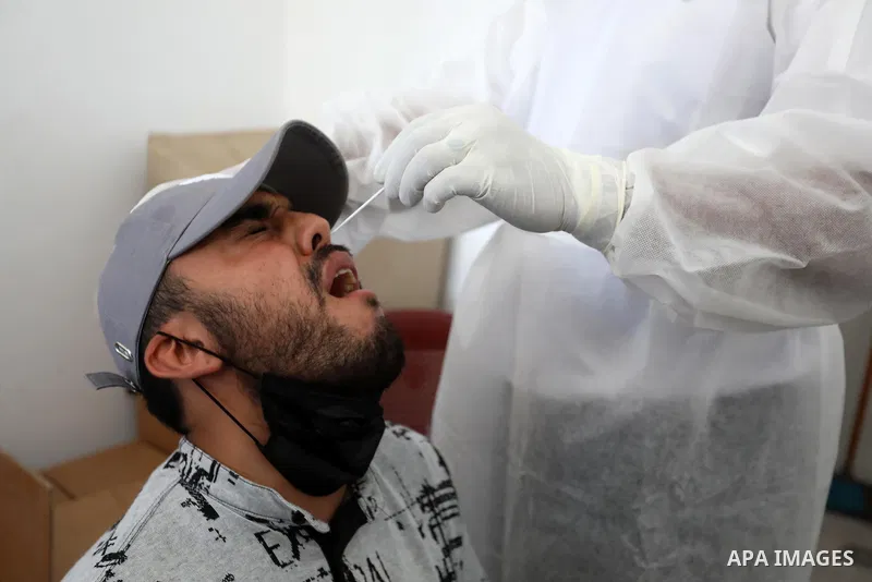 A Palestinian health worker collects a swab sample from a person for Covid-19 test, at a temporary vaccination centre set up in Khan Younis in the southern Gaza Strip on August 23, 2021. Palestinian health officials on M...
